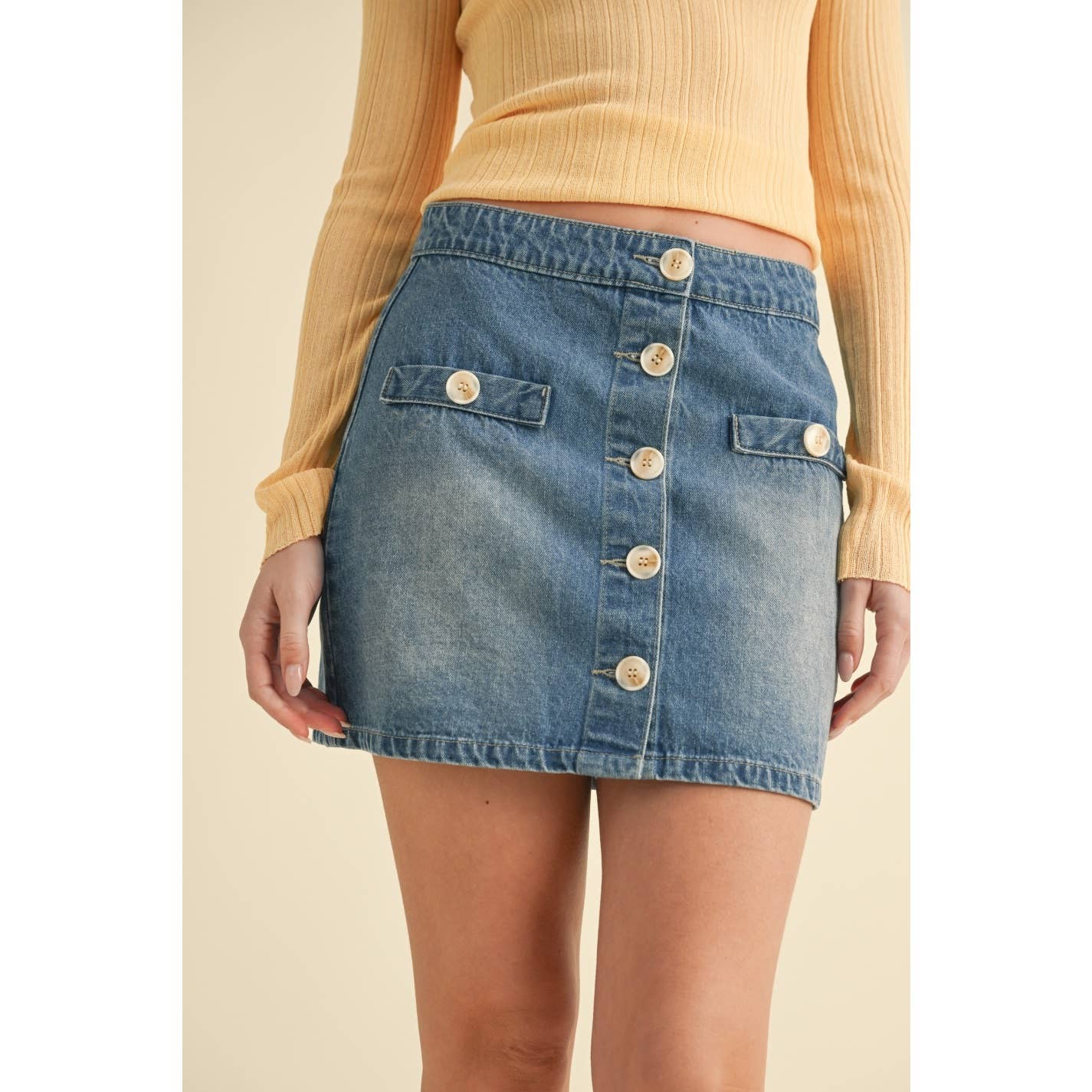 Camellia The Right Track denim skirt, mid-length with classic blue wash, front pockets, and belt loops, styled on a model.