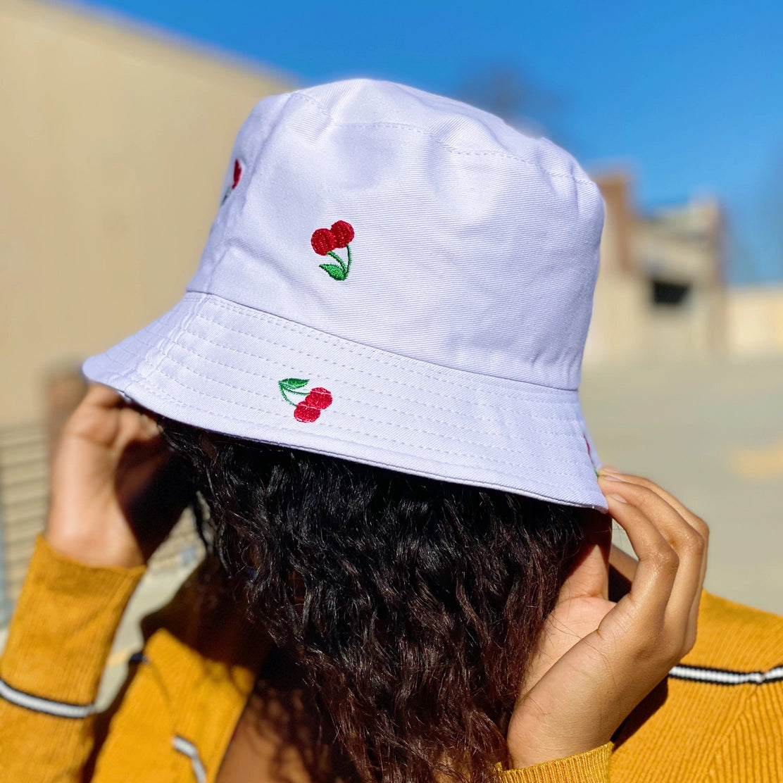 Cherry bucket hat from Can't Hide Pretty Boutique featuring a colorful cherry print and wide brim for sun protection.