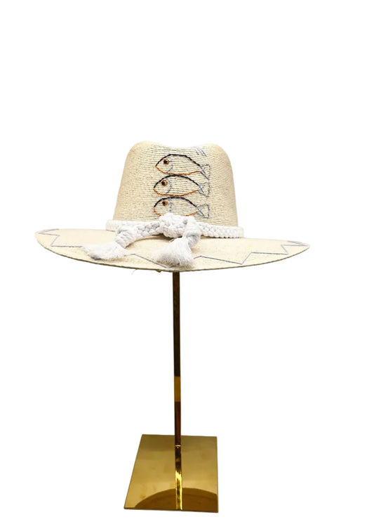 A light beige straw cowboy hat with white crochet lace-up detailing and white tassels, displayed on a gold-colored metal stand against a white background. tipsy threads hat, waterproof hat
summer water boating